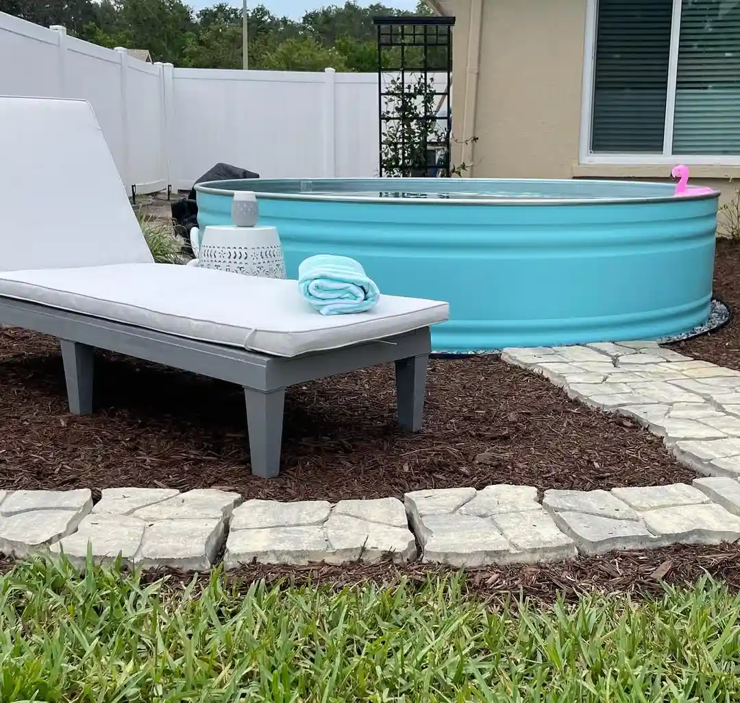 Turquoise Stock Tank Pool with Stone Patio and Lounge Chair